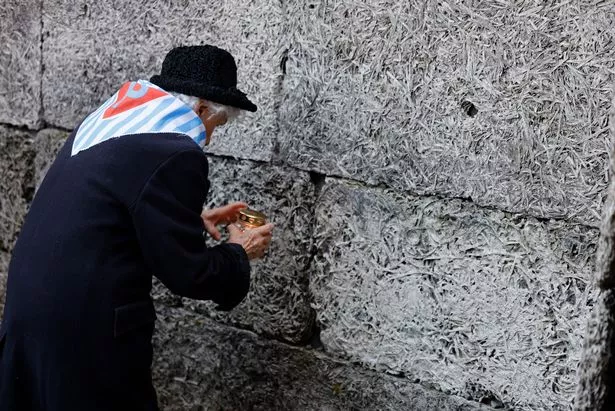 大屠杀幸存者参观奥斯维辛集中营的“死亡墙”，点燃纪念蜡烛的感人场景
